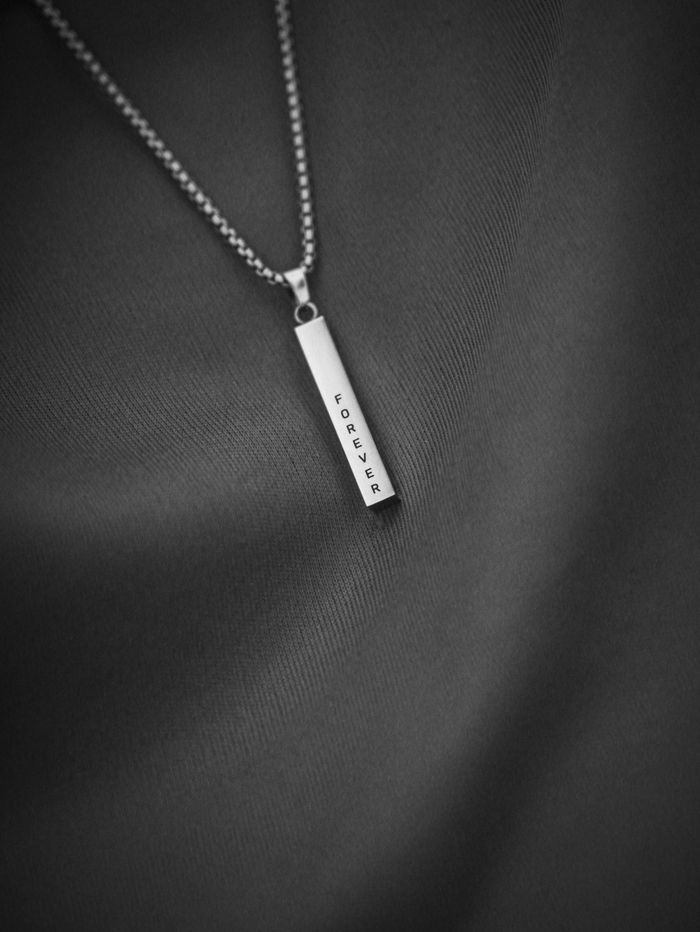 Crafting Captivating Headlines: Your awesome post title goes here Close-up of a necklace with 'Forever' engraving on a textured fabric background.
